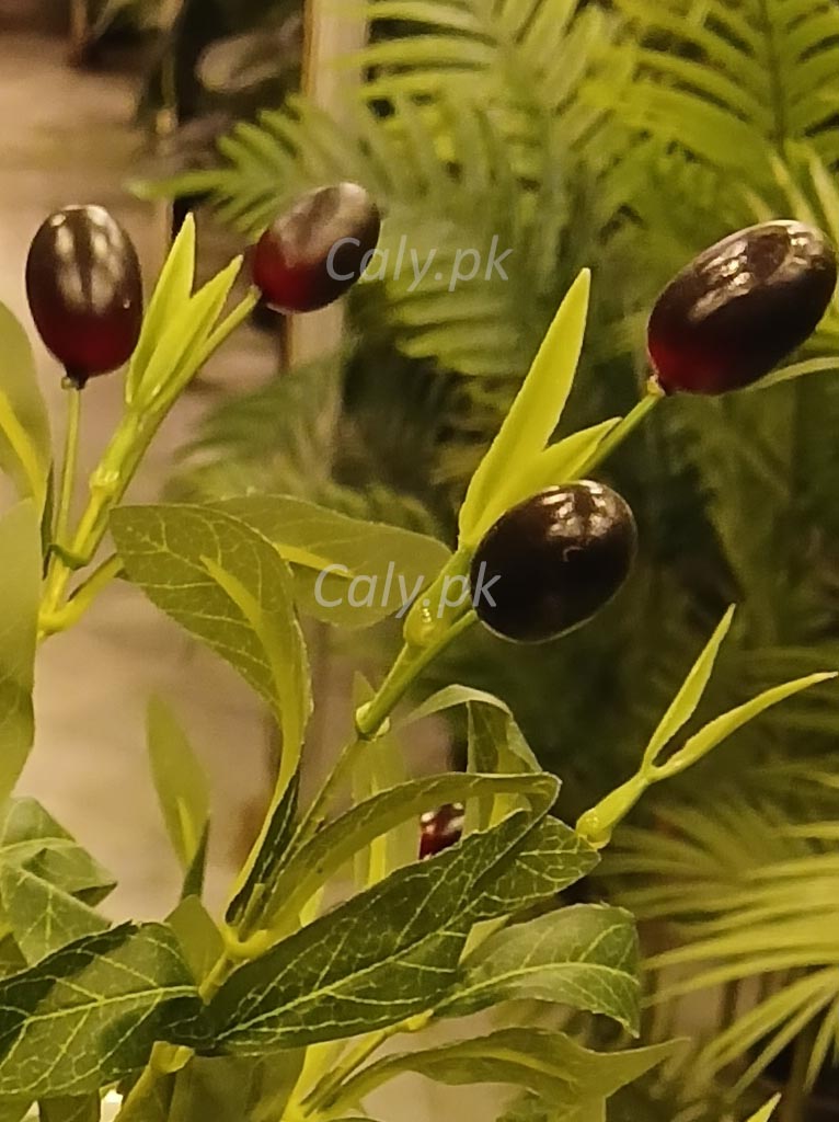 Artificial olive branch with black olives on a blurred green background